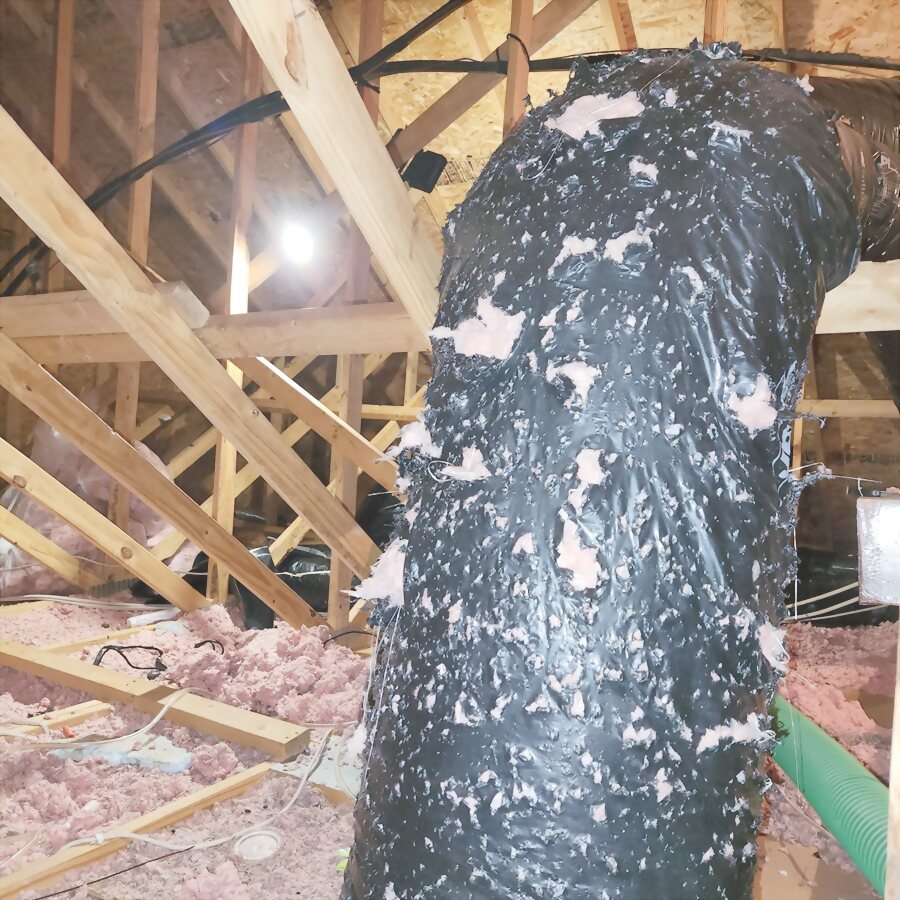 A contaminated duct run in an attic with its wrap torn open.