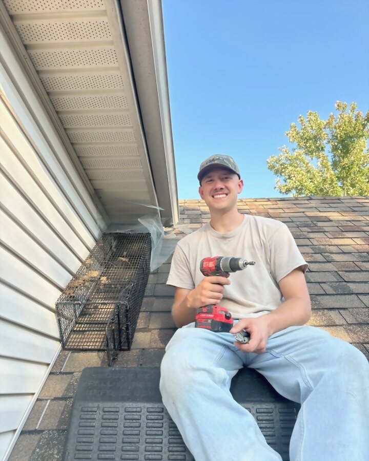 The owner of Central Kentucky Decon, on a roof, sealing a soffit vent.